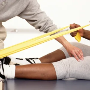 Therapeutische Uebung mit einem gelben Widerstandsband am Bein