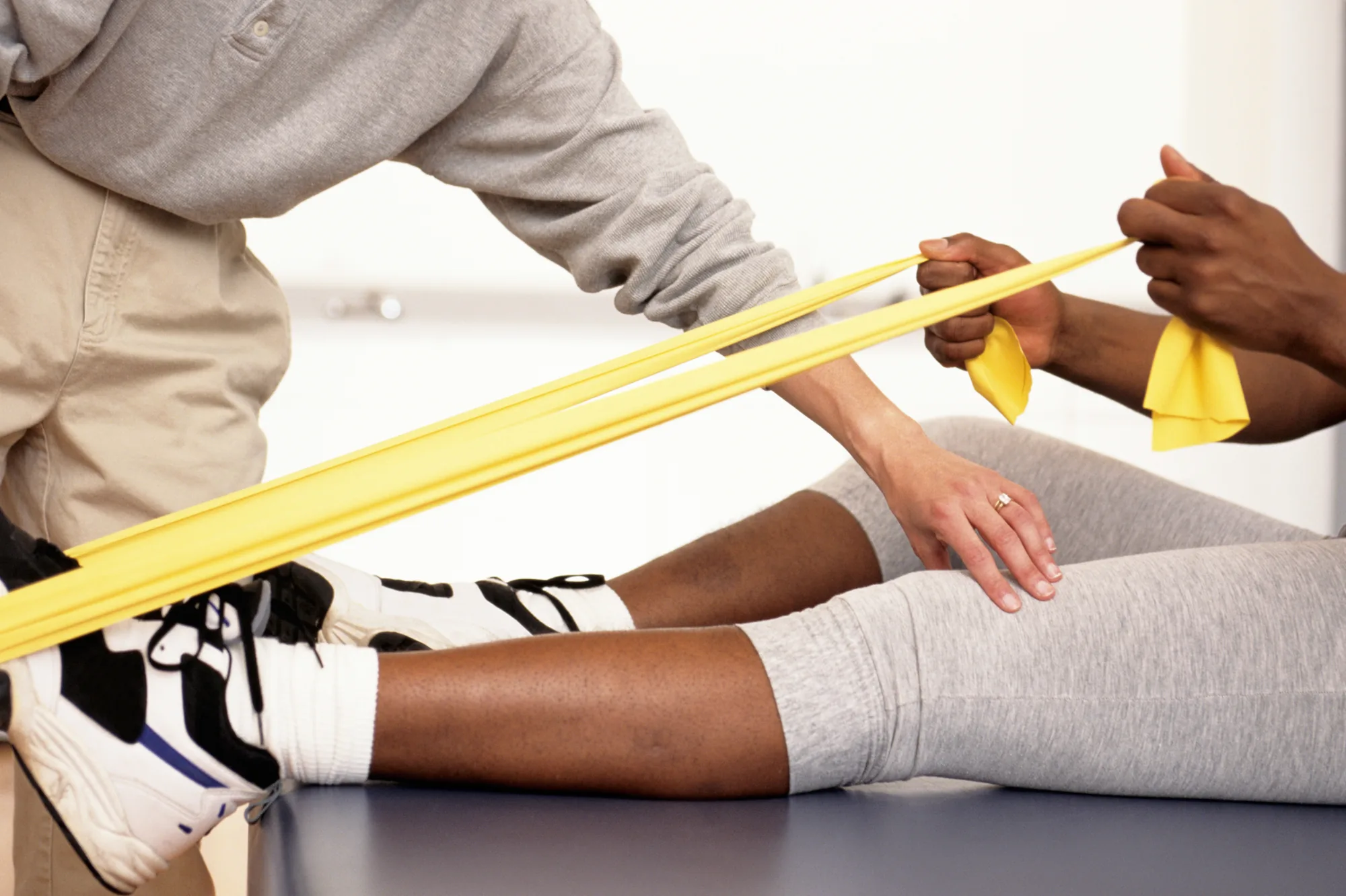 Therapeutische Übung mit einem gelben Widerstandsband am Bein