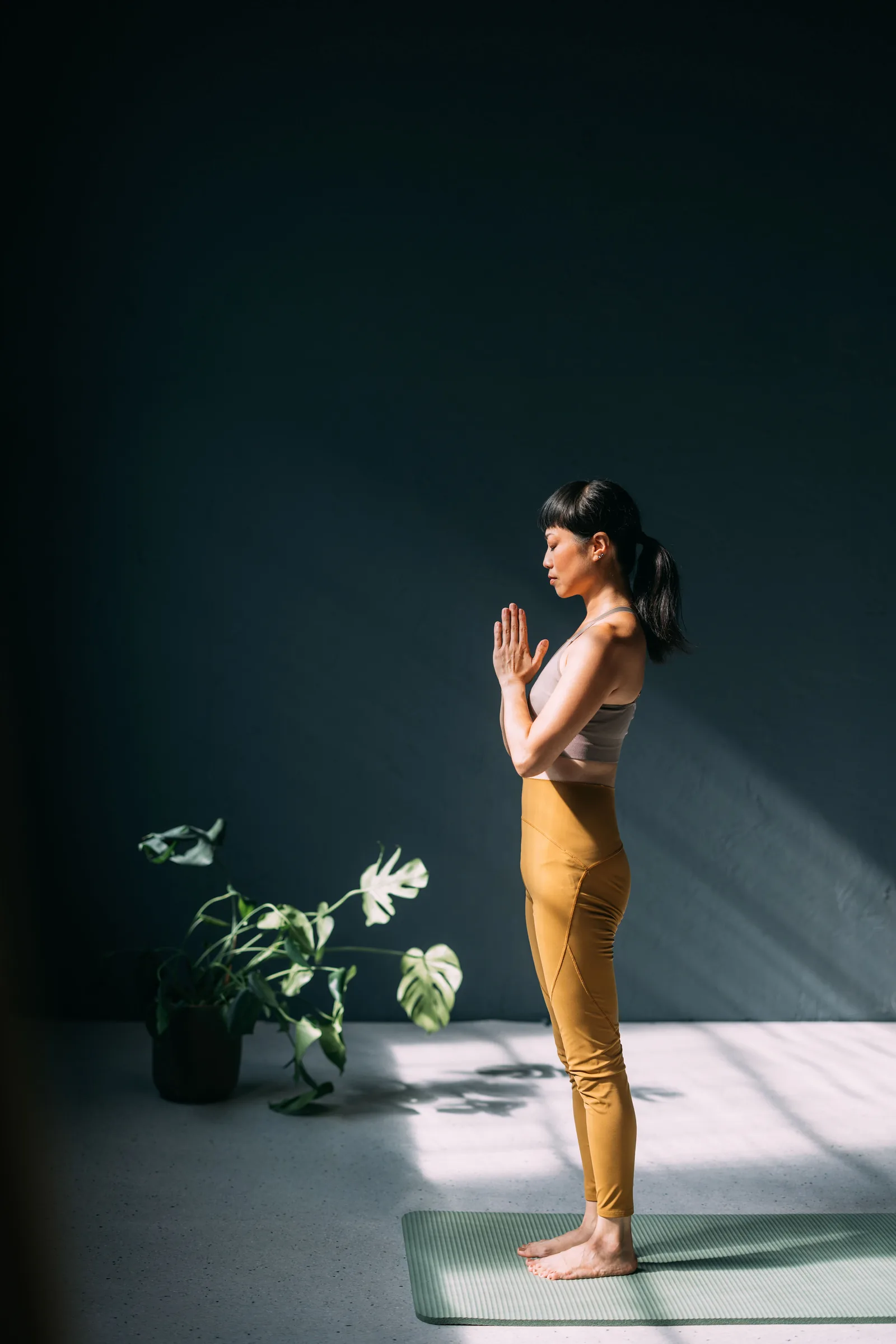 Frau steht in einer Yogahaltung auf einer Matte